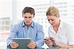 Young businessman and woman using digital tablet and cellphone at a bright office