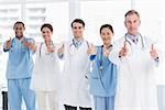 Group portrait of happy confident doctors gesturing thumbs up at hospital