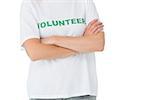 Mid section of a female volunteer standing with arms crossed over white background