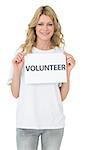 Portrait of a smiling young female volunteer holding placard over white background
