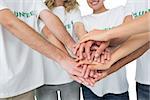 Closeup mid section of volunteers with hands together over white background