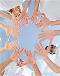 Low angle view of volunteers with hands together against blue sky