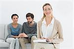 Portrait of a female financial adviser with young couple in background at home