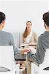 Blurred female financial adviser in meeting with young couple at home