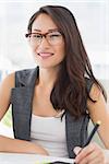 Portrait of a smiling casual female photo editor using graphics tablet in a bright office