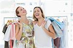 Portrait of two cheerful young women with shopping bags in the clothes store