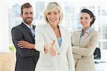 Portrait of a confident businesswoman offering handshake with team in a bright office