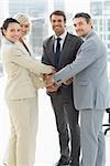 Portrait of business team joining hands together in a bright office
