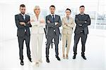 Full length portrait of a confident business team standing with arms crossed in a bright office