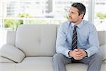 Relaxed well dressed young man sitting on sofa in the house