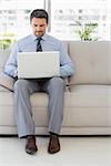 Well dressed relaxed young man using laptop on sofa in the house