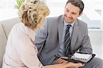 Smart businessman and his secretary  with diary sitting on sofa at home