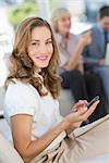 Businesswoman text messaging with colleagues using laptop in background at home