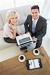 High angle portrait of a businessman and his secretary with laptop and diary sitting on sofa at home