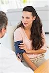 Male doctor checking blood pressure of a young woman at the medical office