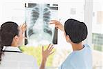 Rear view of two female doctors examining xray in the medical office