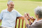 Senior woman photographing man while sitting on bench at the park