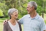 Happy senior woman and man with arms around at the park