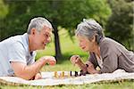 Side view of a happy senior couple playing chess at the park