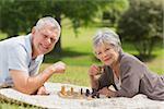 Side view of a happy senior couple playing chess at the park