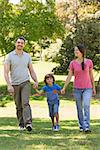 Portrait of a family of three holding hands and walking at the park