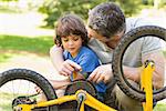 Closeup of father and son fixing bike