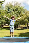 Full length of a happy boy jumping high on trampoline  in the park