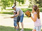 Family of three playing baseball in the park
