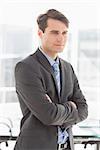 Handsome focused businessman with arms crossed in the office