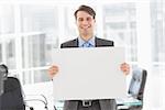 Handsome happy businessman holding placard in the office