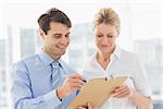 Smiling business team looking at clipboard together in the office