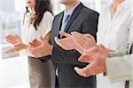 Business team standing in a row applauding in the office