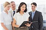 Businesswoman reading a document with her team in the office