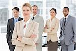 Businesswoman looking at camera with team behind her in the office