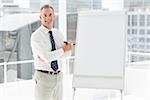 Smiling businessman standing at whiteboard with marker in the office