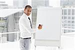 Young businessman presenting at whiteboard with marker in the office