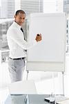 Young smiling businessman presenting at whiteboard with marker in the office