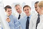 Young businessman writing on whiteboard with colleagues in the office