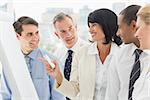 Colleagues watching happy businesswoman pointing to whiteboard in the office