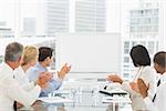 Business people applauding blank whiteboard in conference room in the office