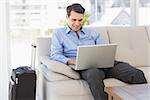 Travelling businessman using laptop sitting on the couch in the office