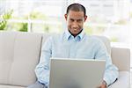 Smiling businessman working on laptop on the couch in the office