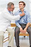 Doctor listening to his patients chest with stethoscope in his office at the hospital