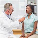 Doctor listening to patients chest with stethoscope in his office at the hospital