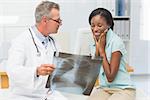 Doctor showing young patient her positive chest xray in his office at the hospital