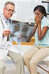 Doctor showing pleased patient her positive chest xray in his office at the hospital