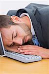 Closeup of a young businessman resting with head over keyboard at desk in the office