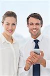 Smartly dressed young man and woman with a mobile phone in bright office
