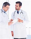 Concentrated two male doctors using digital tablet in a bright medical office