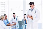 Doctor using digital tablet with colleagues in meeting at a medical office